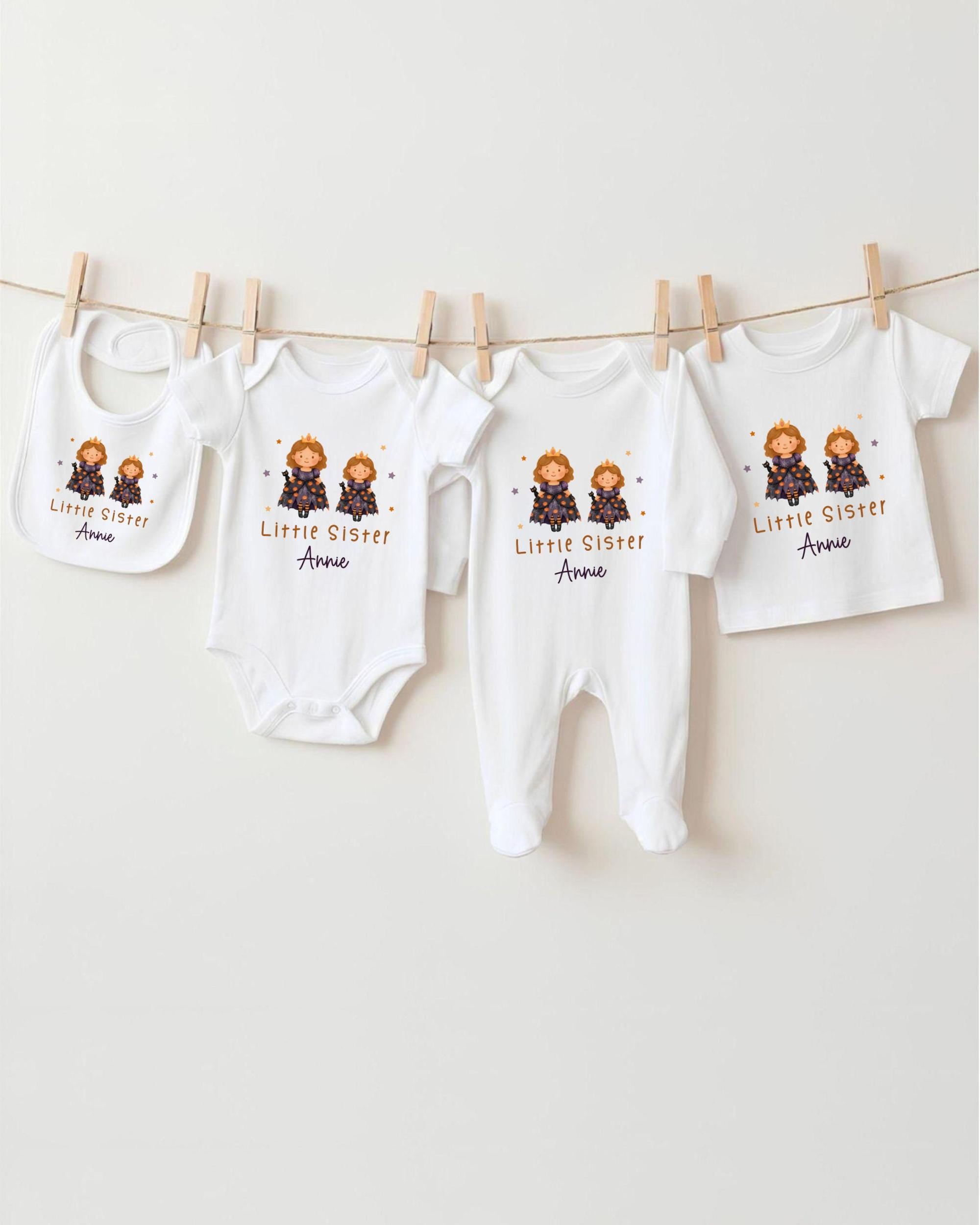 A row of four white baby clothes, including onesies and pajamas, hanging on a clothesline.