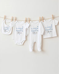 A row of four white baby clothes with the text "Little Cousin Oliver" printed on them, hanging on a clothesline.