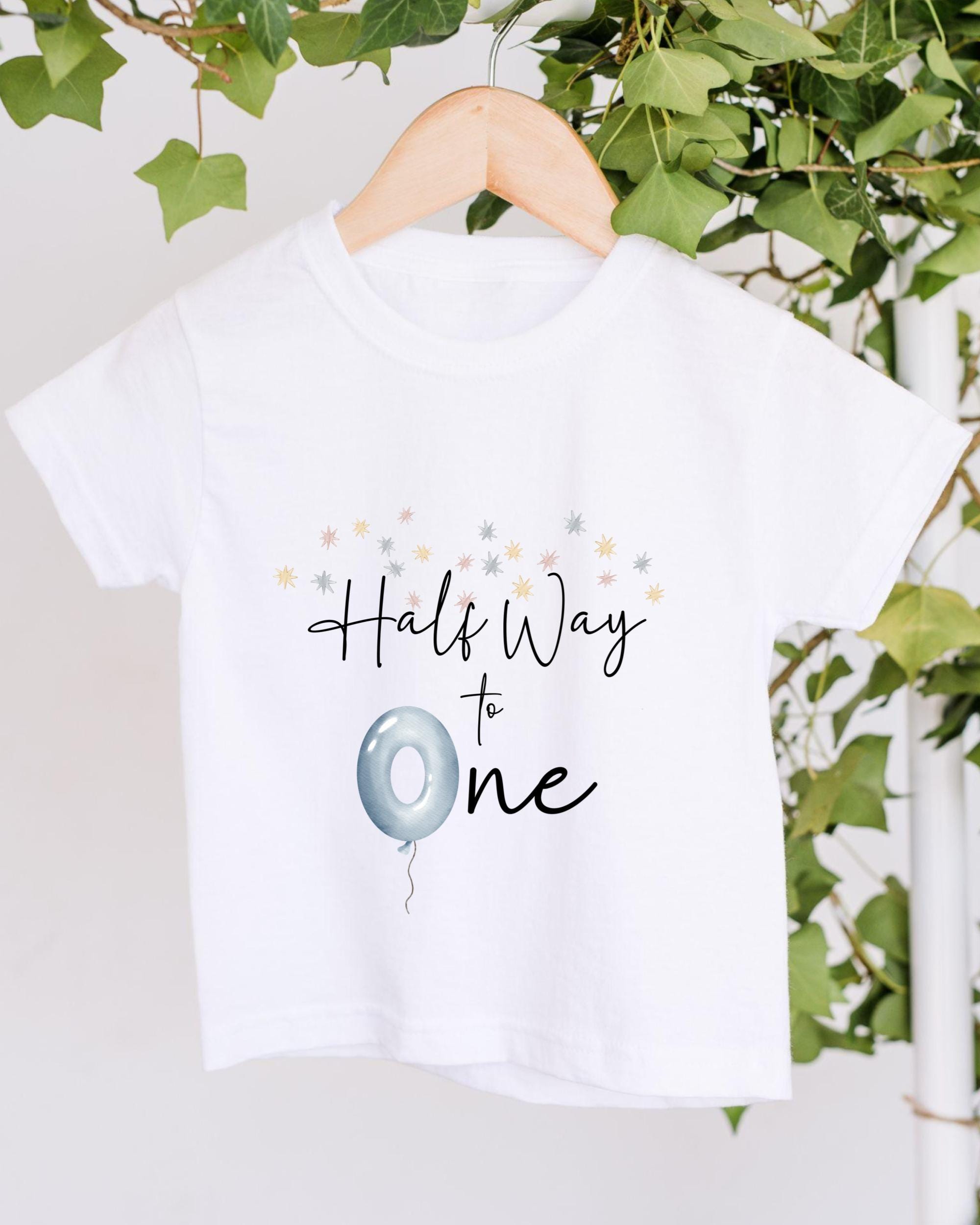 A white t-shirt with a graphic design and text printed on it, hanging on a wooden hanger.