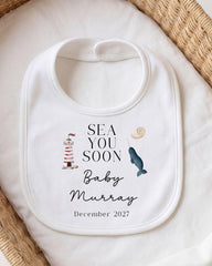 a white bib with a personalized message and illustrations related to a baby announcement.