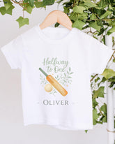 A white t-shirt with a graphic design and text printed on it, hanging on a wooden hanger.