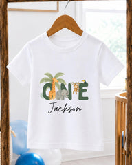 A white t-shirt with a personalized name and animal print design hanging on a wooden hanger.