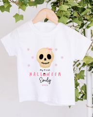 A white t-shirt with a skull design and text printed on it, hanging on a wooden hanger.