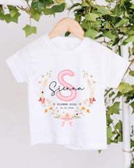 A white t-shirt with a floral design and the name "Siena" printed on it, hanging on a wooden hanger.