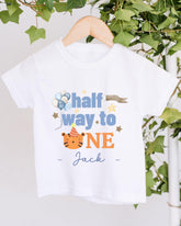 A white t-shirt with a printed design that says "half way to one" and features a tiger wearing a party hat.