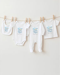 A collection of baby clothes, including onesies and bibs, hanging on a clothesline.