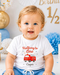 A smiling baby boy wearing a white t-shirt with a red fire truck graphic and the text "Halfway to One - Casper" printed on it.