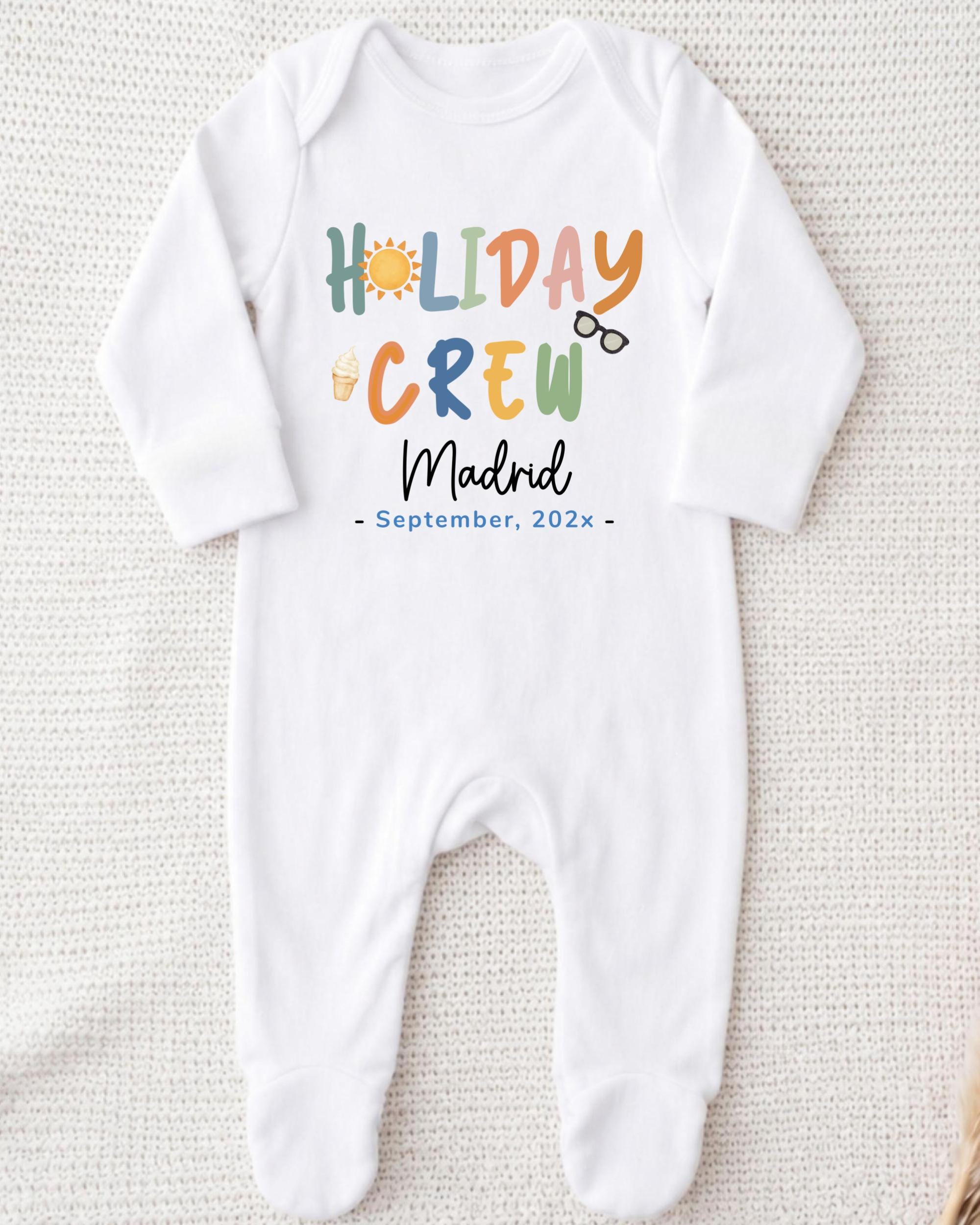 A white onesie with the text "HOLIDAY CREW Madrid September 202x" printed on it.