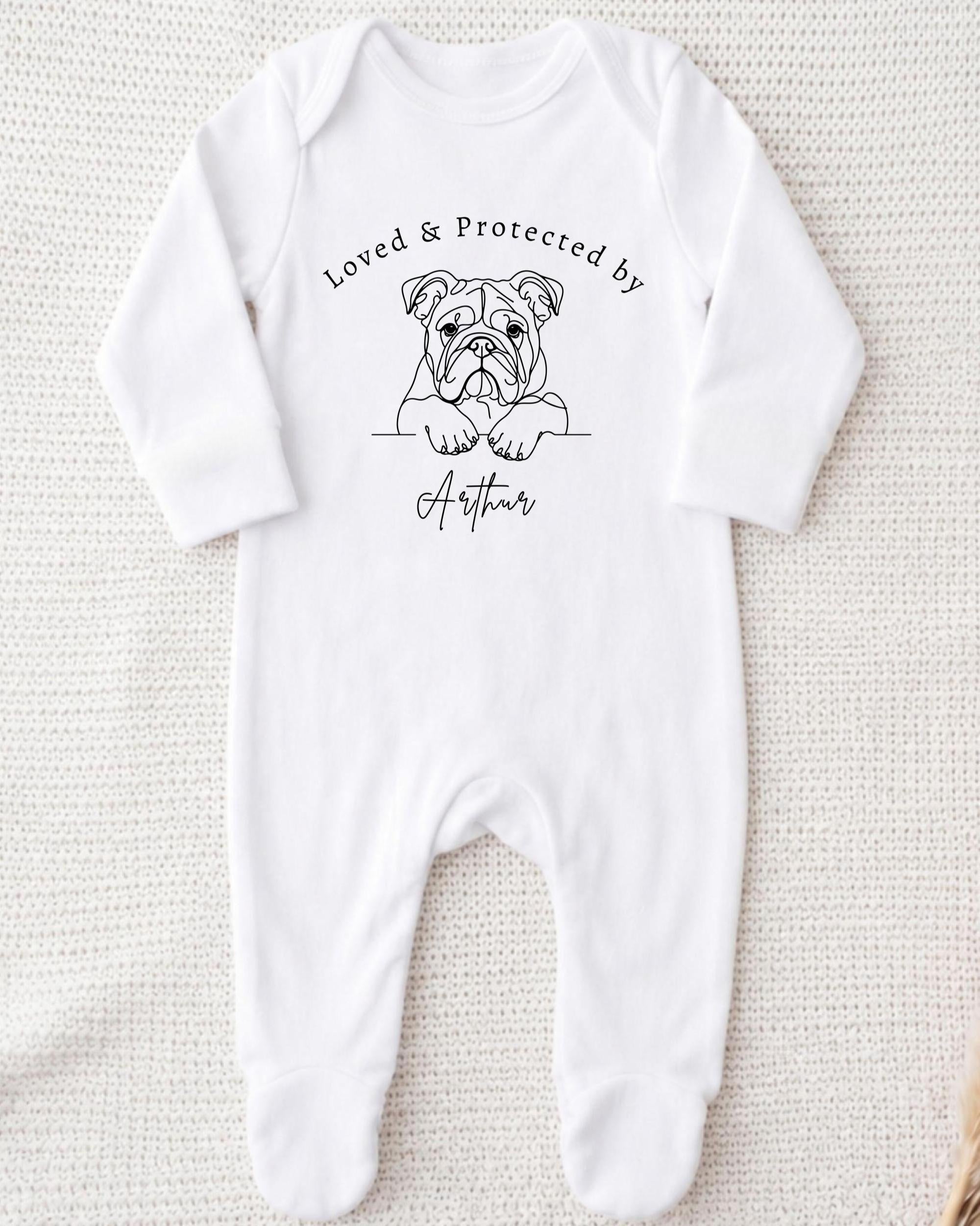 A white onesie with a black illustration of a bulldog and the text "Loved & Protected by Arthur" printed on it.
