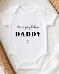 A white baby onesie with the text "You're going to be a DADDY" printed on it.