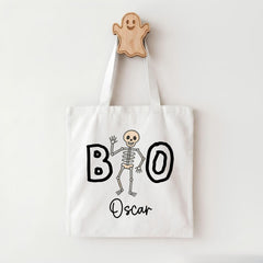 A white tote bag with a skeleton and the word "BOO" printed on it, along with the name "Oscar" below the skeleton.