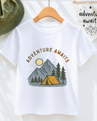 A white t-shirt with a graphic design depicting a camping scene with mountains, pine trees, and a tent, along with the text "Adventure Awaits" printed on it.
