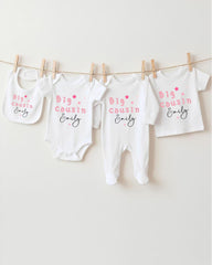 A row of four white baby clothes with pink text and stars hanging on a clothesline.