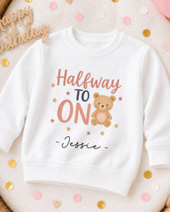 A white sweatshirt with a teddy bear and the text "Halfway to ON" printed on it, along with the name " Jessie" written below.