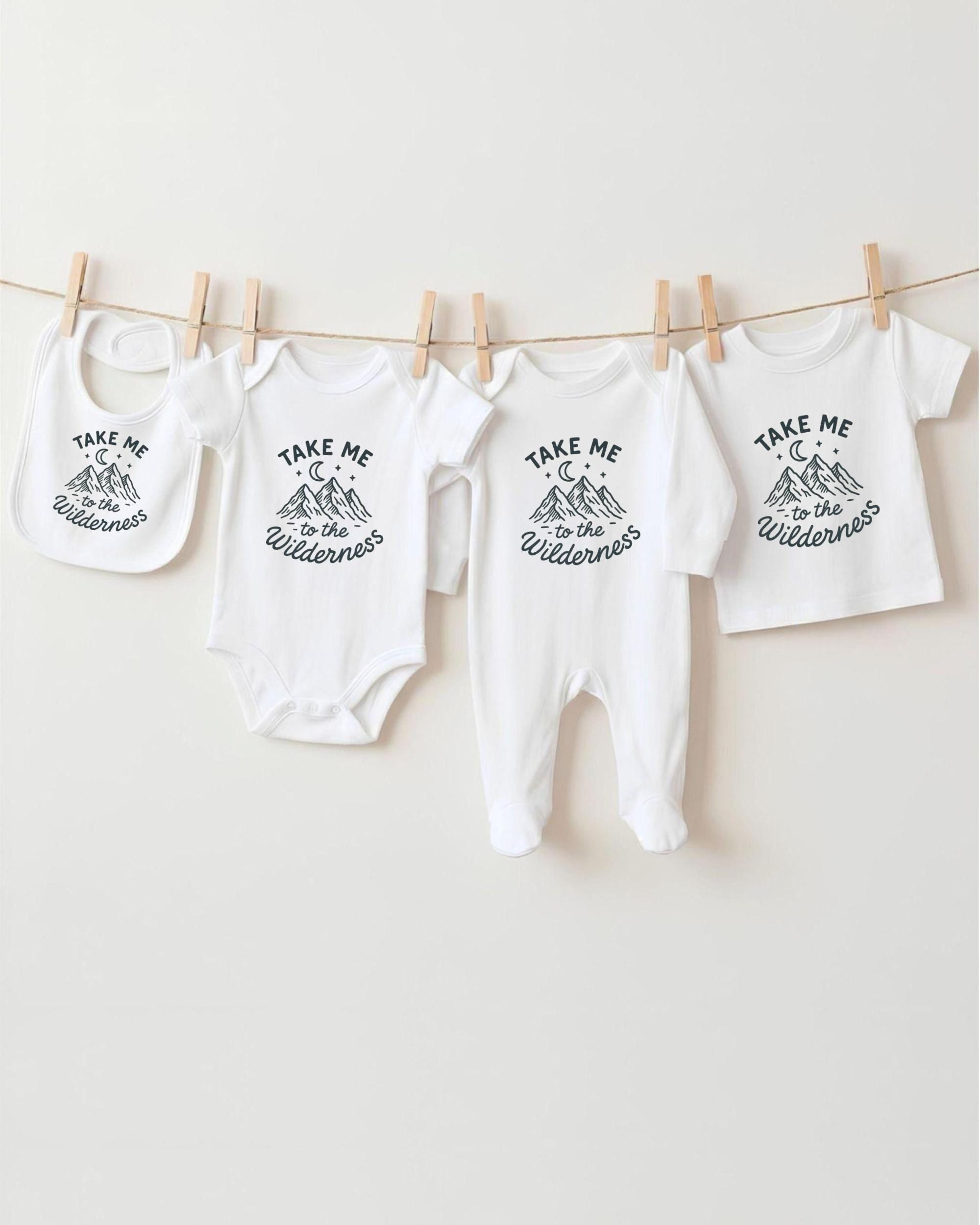 A collection of baby clothes, including onesies and bibs, hanging on a clothesline.