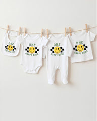 A collection of four white baby clothes with a cheerful yellow smiley face design, hanging on a clothesline.