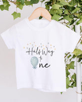A white t-shirt with a graphic design and text printed on it, hanging on a wooden hanger.