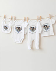 A collection of white baby clothes, including onesies and pajamas, hanging on a clothesline.