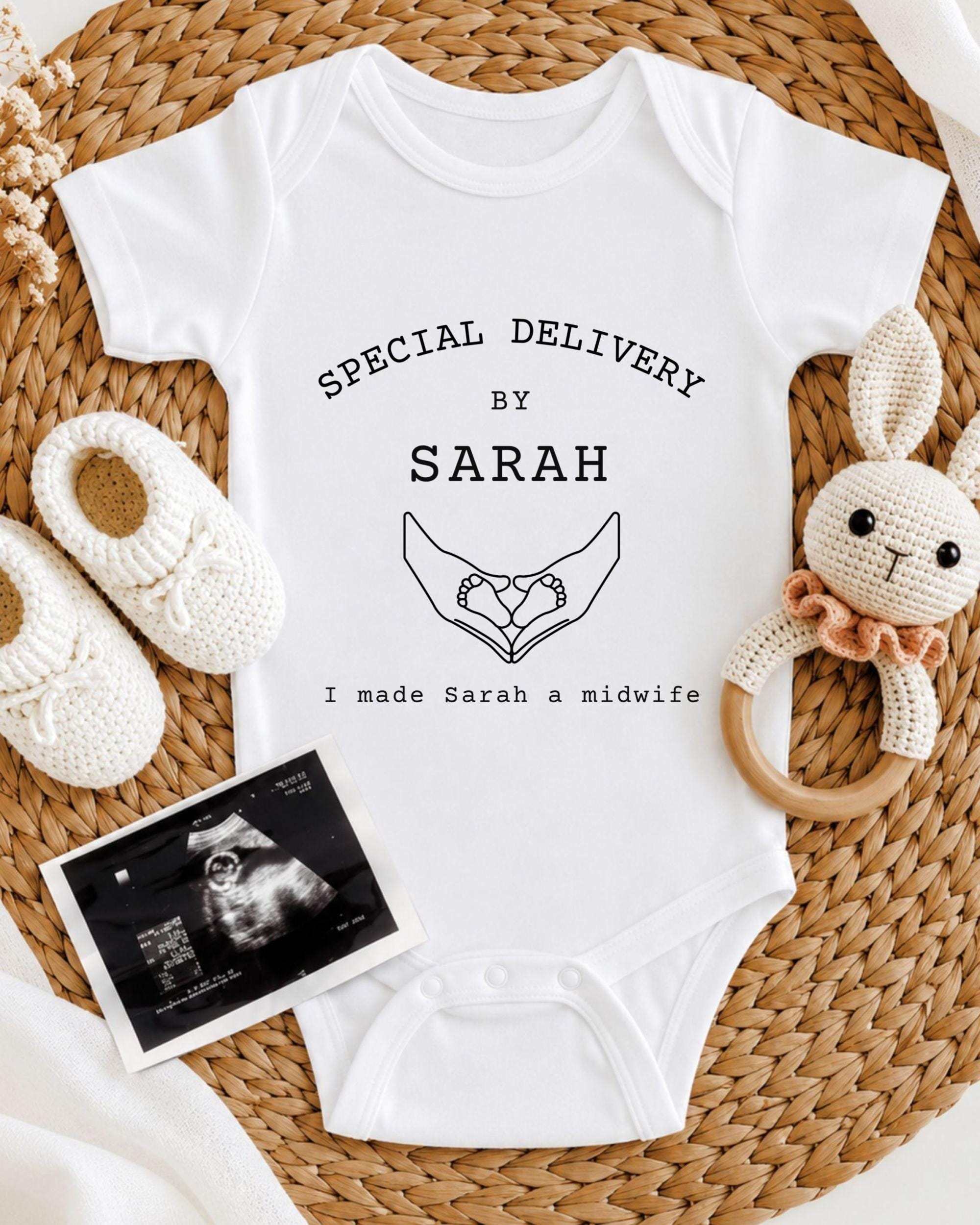 A white onesie with text and a handprint graphic, a crocheted stuffed rabbit, and a baby bootie, all arranged on a woven placemat.