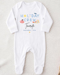 A white onesie with the text "HOLIDAY CREW" and "Tenerife" printed on it, along with illustrations of a sun, sunglasses, and a beach scene.
