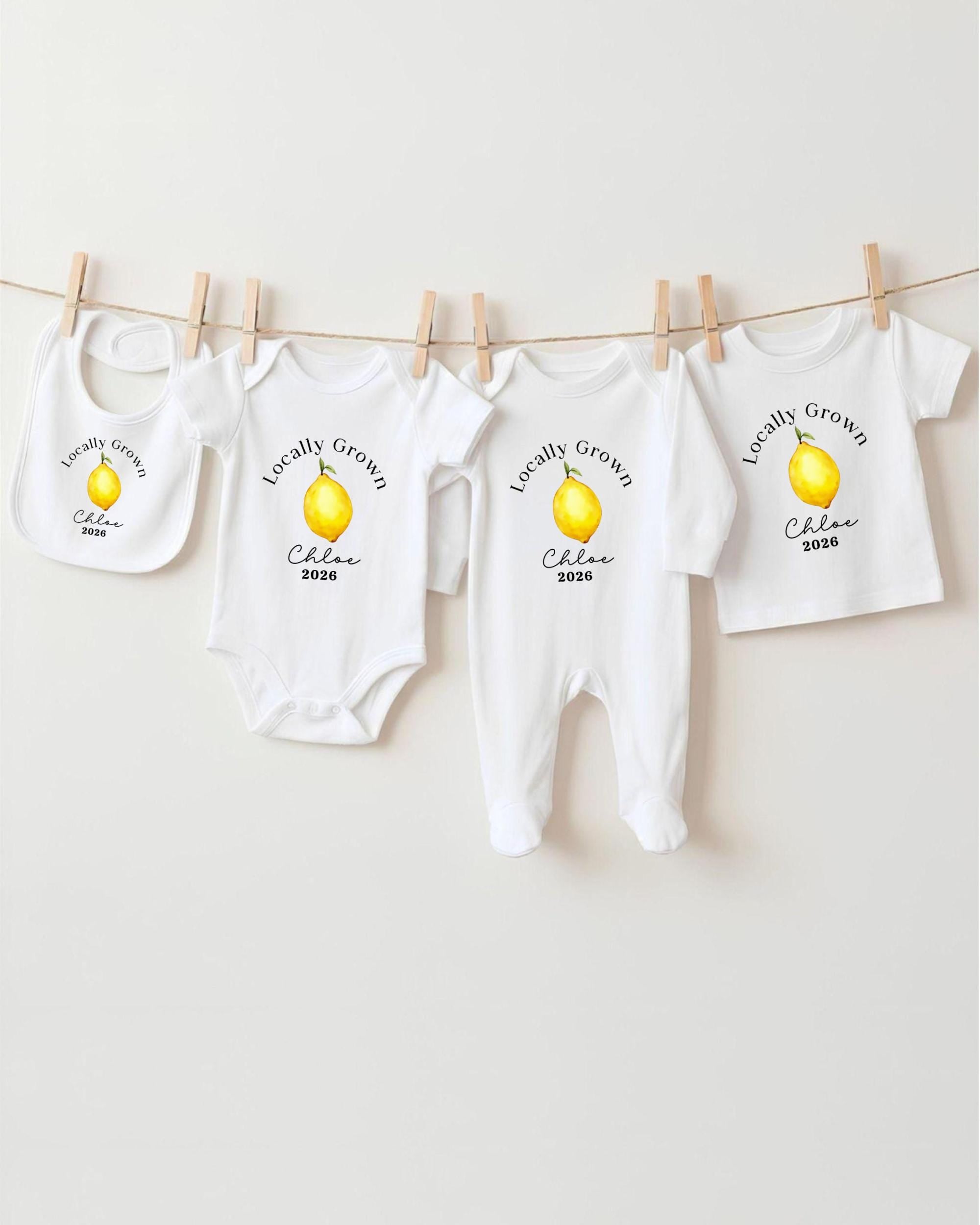 A row of white baby clothes with a yellow lemon graphic, each with a personalized name and year printed on them.