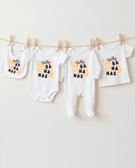 A collection of baby clothes, including onesies and bibs, hanging on a clothesline.
