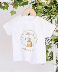 A white t-shirt with a graphic design featuring a hedgehog and the text "Halfway to One - Mario" hanging on a wooden hanger.