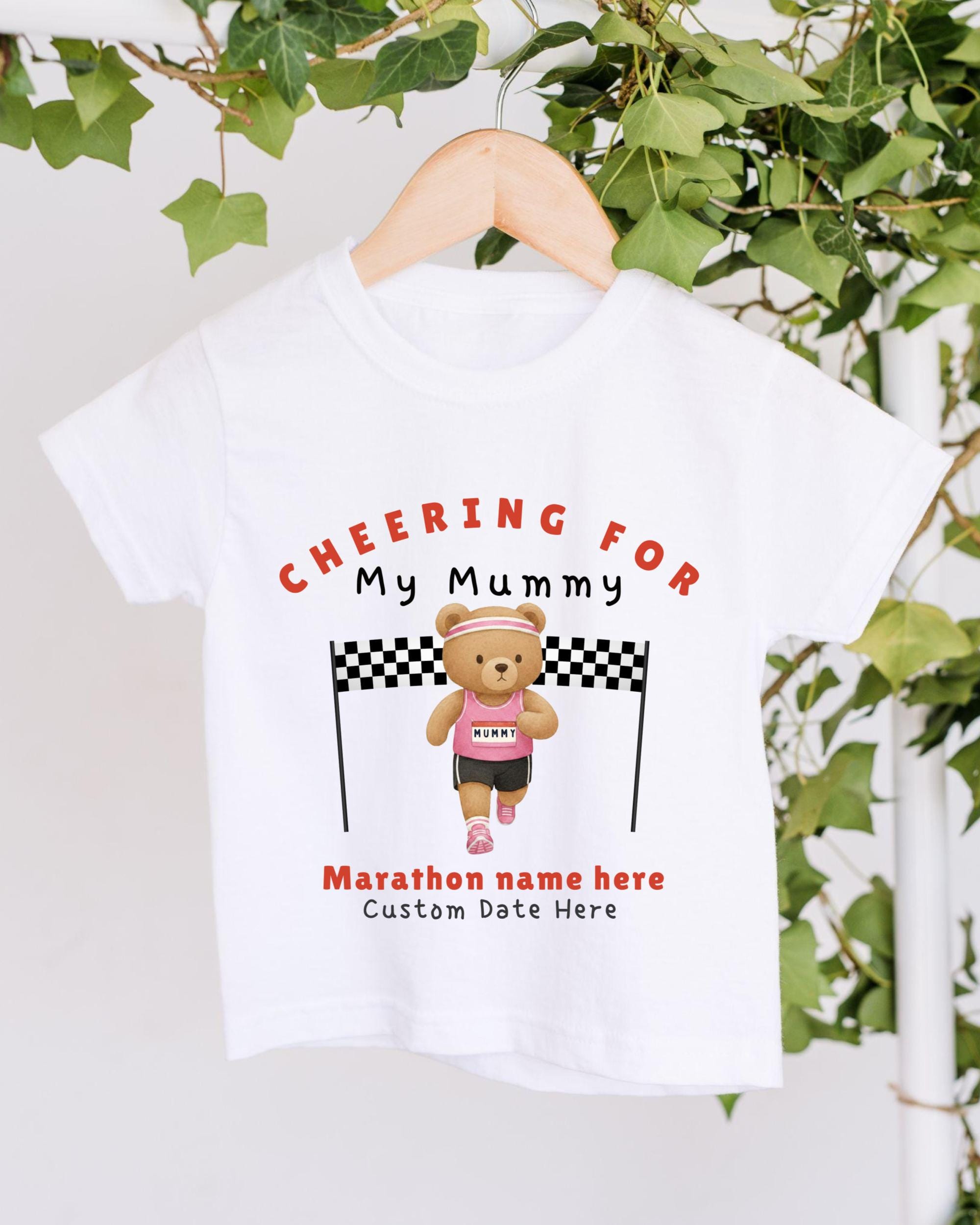 A white t-shirt with a graphic design featuring a teddy bear wearing a pink shirt and running with a checkered flag, along with the text "CHEERING FOR My Mummy" and "Marathon name here Custom Date Here".
