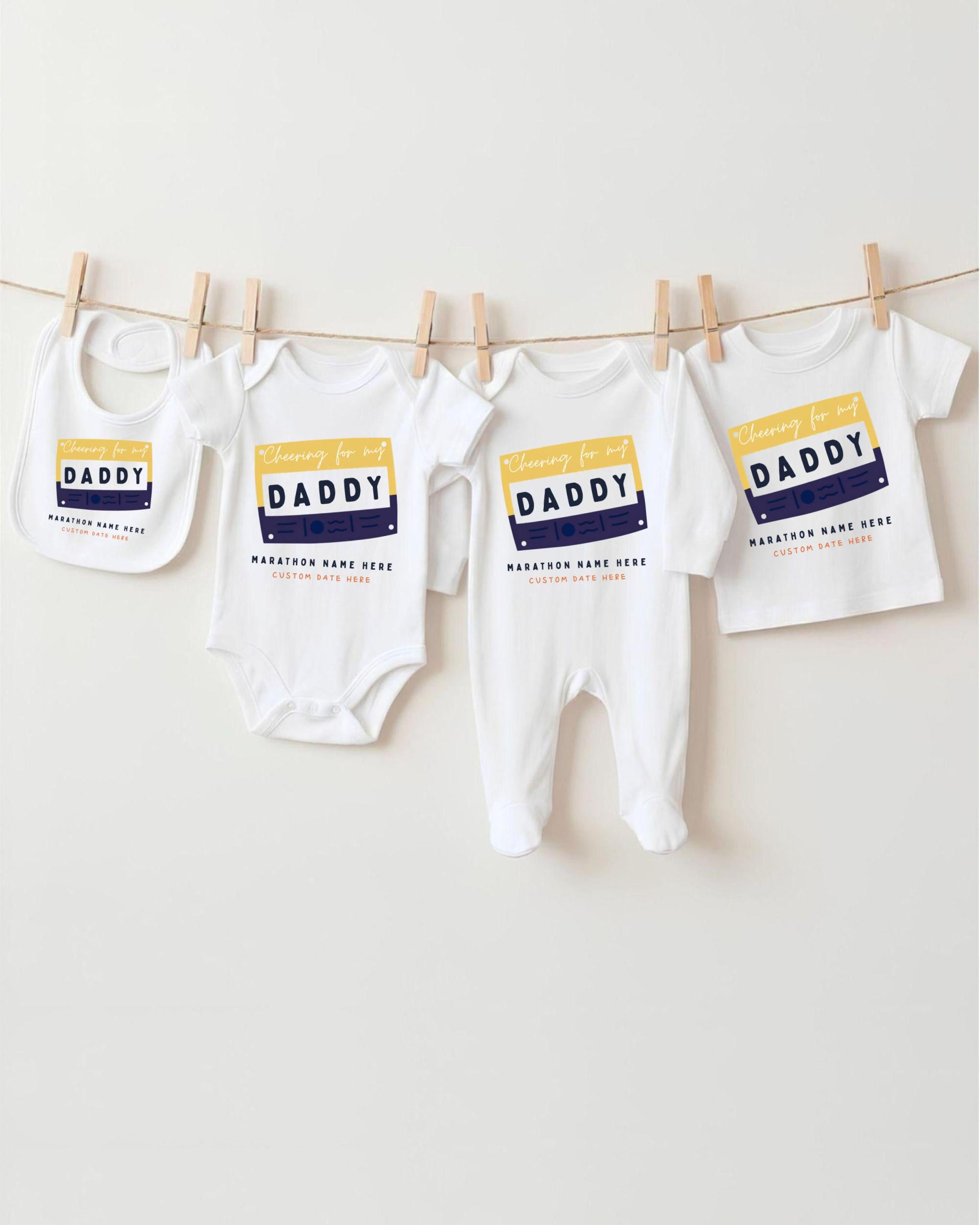 A row of four white baby clothes with the word "DADY" printed on them, hanging on a clothesline.