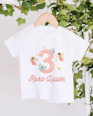 A white t-shirt with a pink number 3 and a design of two angels, along with the text "Rosa Louise" printed on it.