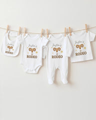 A collection of baby clothes, including onesies and rompers, hanging on a clothesline.