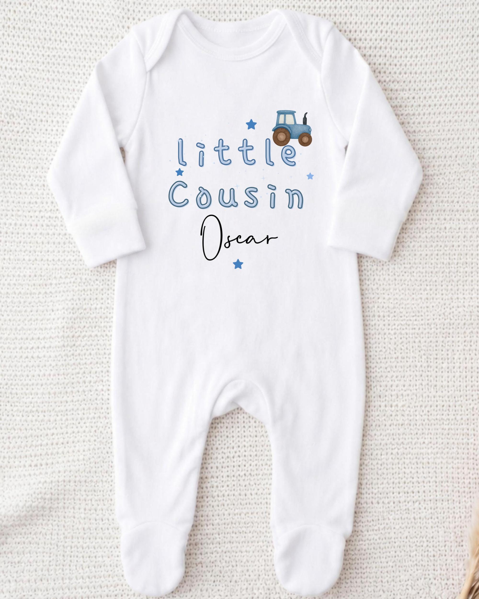 A white onesie with blue text and a tractor graphic printed on it.