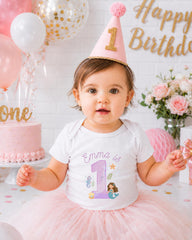 A young girl wearing a pink party hat and a white t-shirt with a mermaid design is posing for a birthday photo.