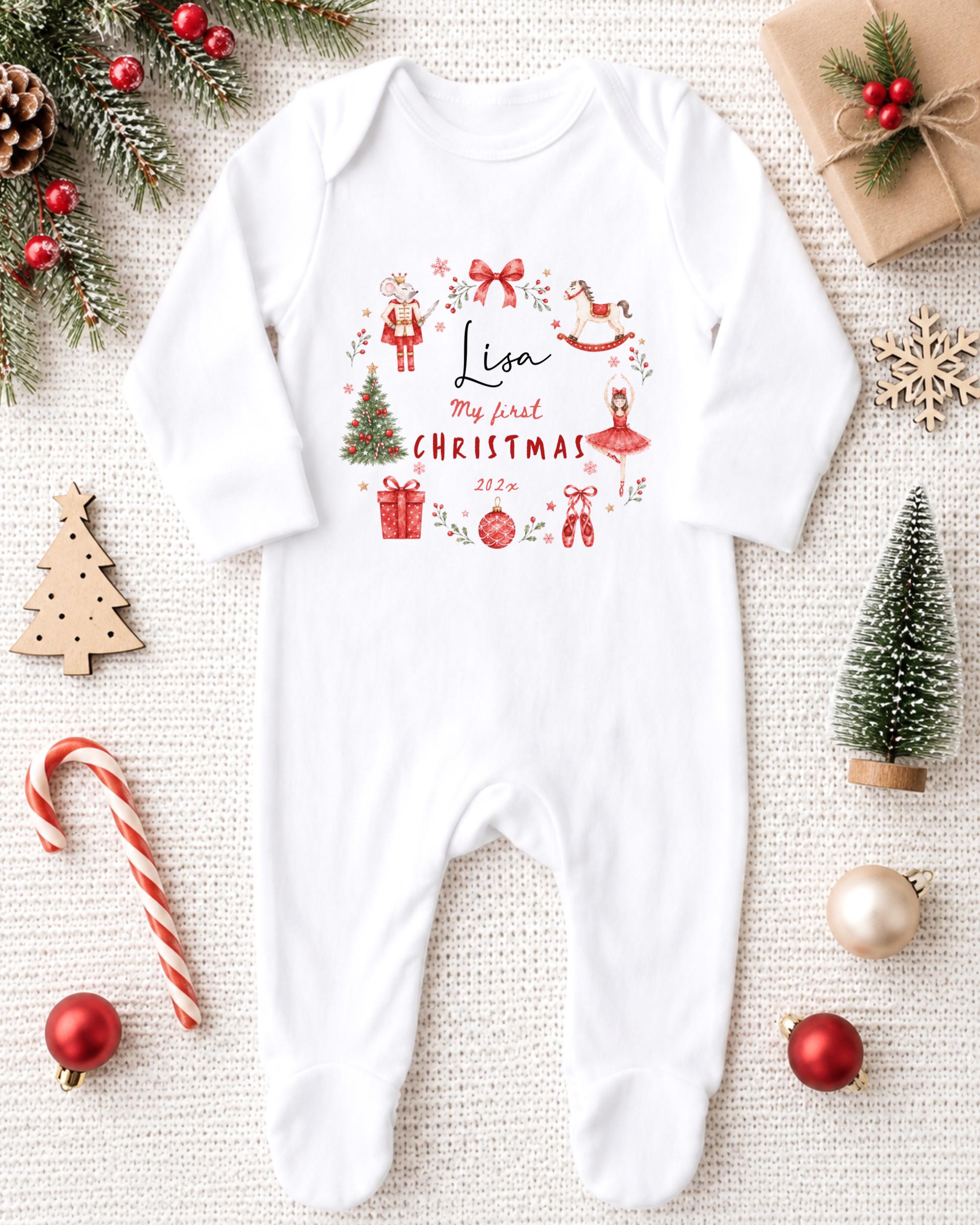 A white onesie with a Christmas-themed design, surrounded by various Christmas decorations and gifts, including a small Christmas tree, ornaments, and a candy cane.