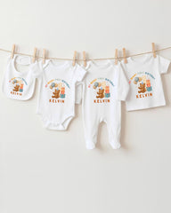 A collection of baby clothes, including onesies and bibs, hanging on a clothesline.