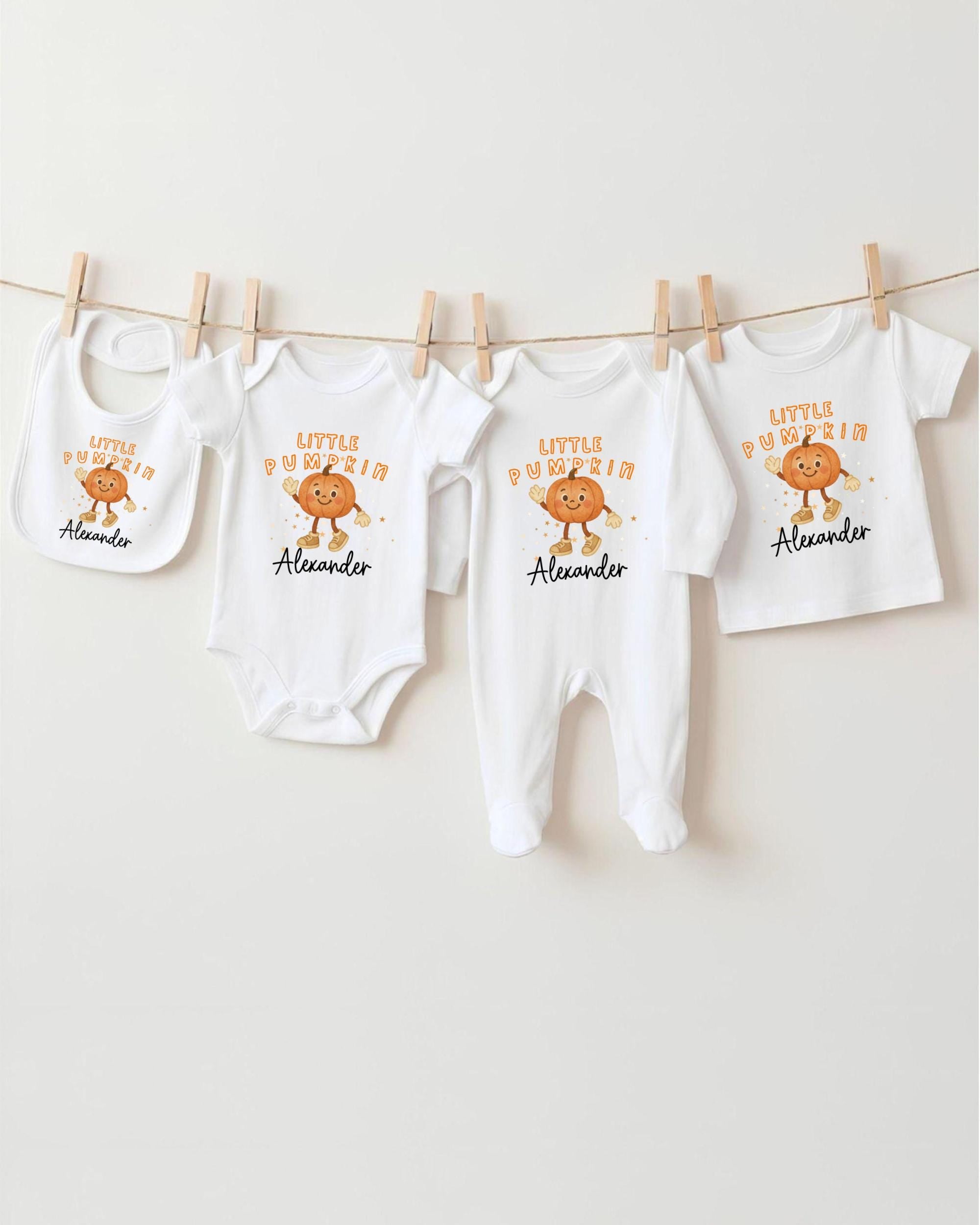 A row of white baby clothes with orange pumpkin characters on them, hanging on a clothesline.