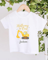 A white t-shirt with a yellow construction vehicle graphic and the text "Halfway to One - Jackson" printed on it.