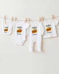 A row of four white baby clothes with the name "Oscar" printed on them, hanging on a clothesline.
