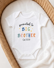 A white baby onesie with text that reads "promoted to BIG BROTHER Est 2029" printed on it.