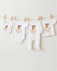 A row of four white baby clothes with Halloween-themed designs hanging on a clothesline.