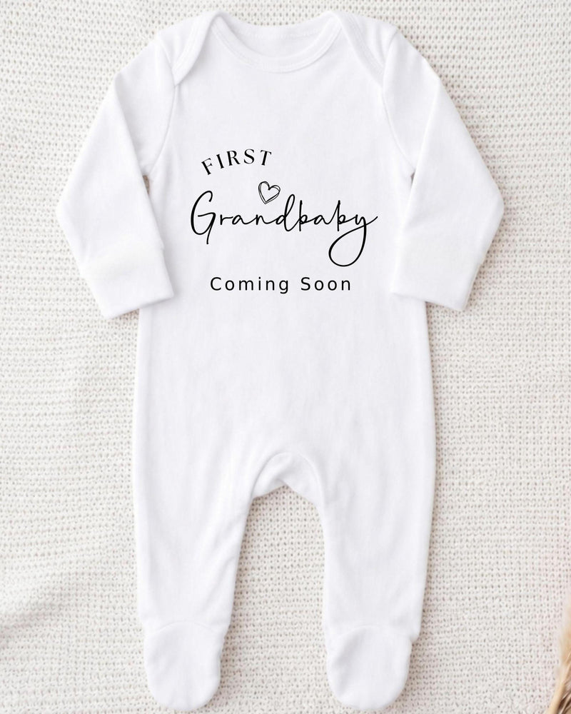 Personalised white Bib with black 'First Grandbaby Coming Soon' lettering and an outline heart for a grandparents pregnancy announcement.