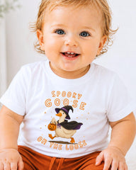 A smiling baby wearing a white t-shirt with a graphic of a goose dressed as a witch and the text "Spooky GOOSE ON THE LOOSE" printed on it.