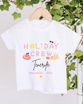 A white t-shirt with the text "HOLIDAY CREW Tenerife" printed on it, along with various summer-themed illustrations such as sunglasses, a beach ball, and a hot dog.