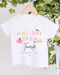 A white t-shirt with the text "HOLIDAY CREW Tenerife" printed on it, along with various summer-themed illustrations such as sunglasses, a beach ball, and a hot dog.