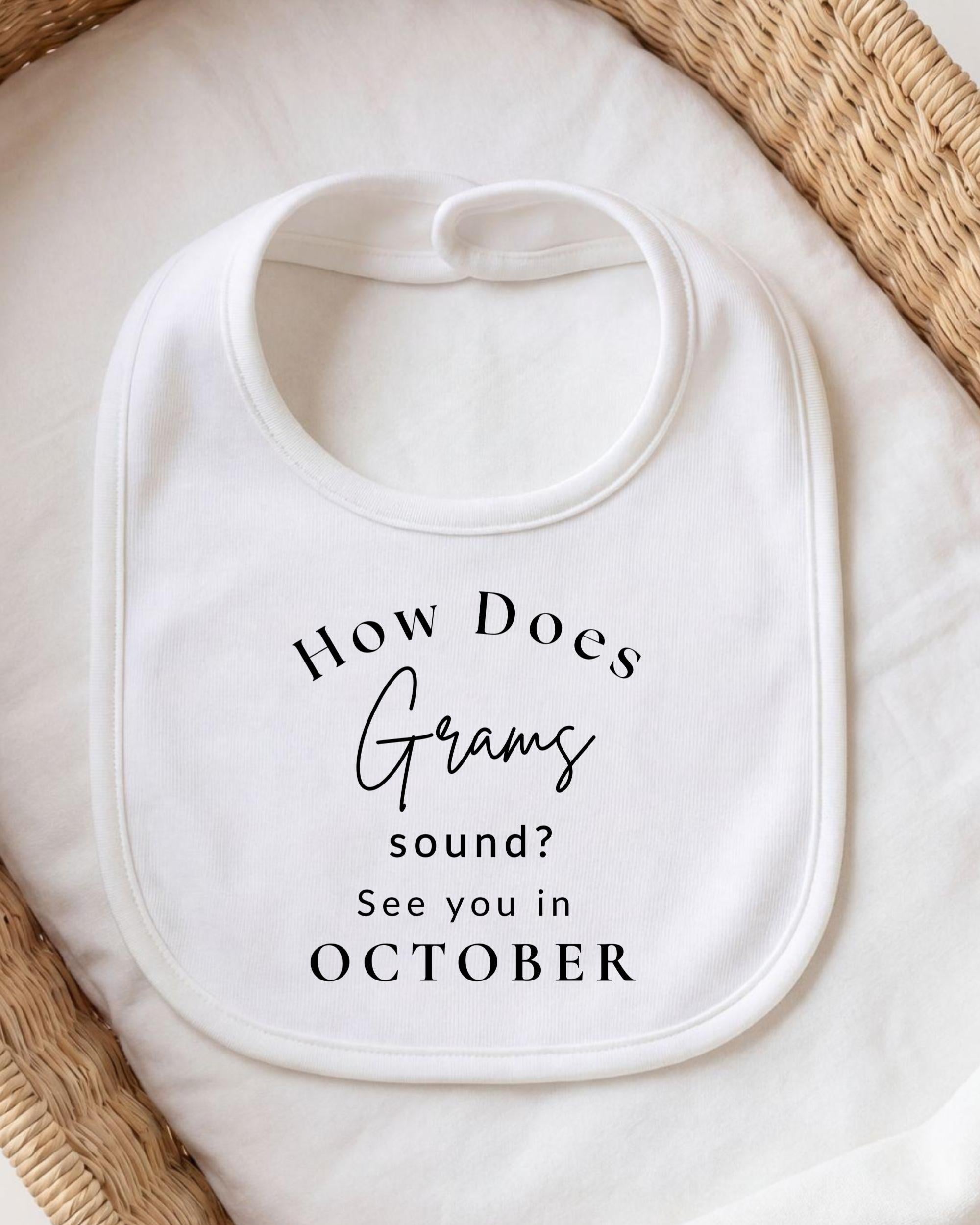 A white bib with the text "How Does Gram sound? See you in October" printed on it.