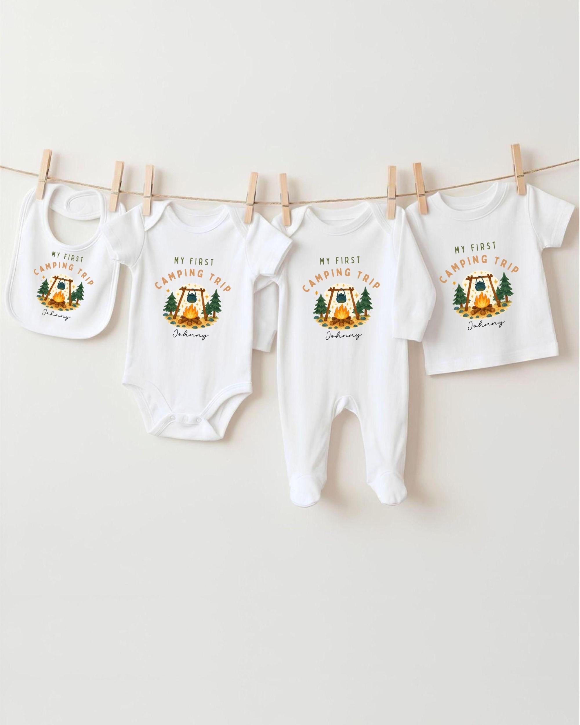 A collection of four white baby clothes, including onesies and bibs, hanging on a clothesline.