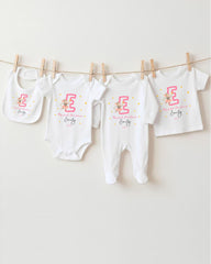 A collection of white baby clothes, including onesies and bibs, hanging on a clothesline.
