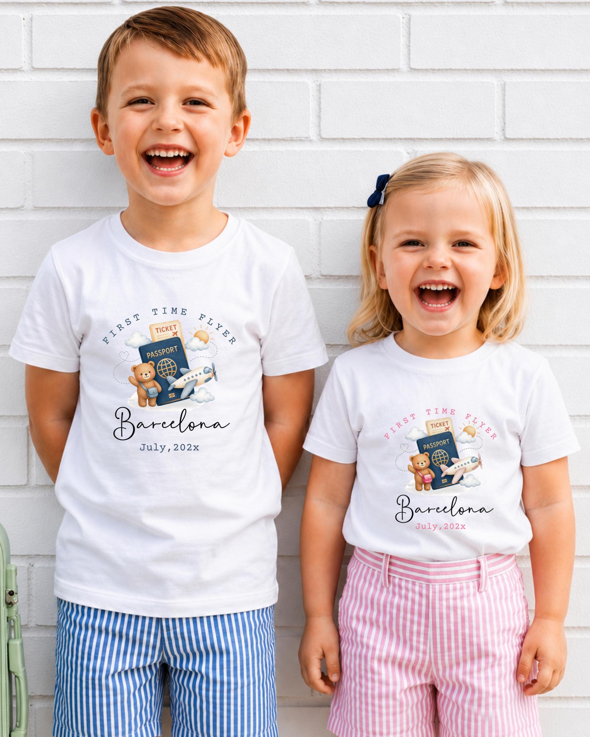Two children, a boy and a girl, are standing next to each other and smiling, wearing matching white t-shirts with a graphic design and text.