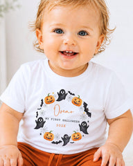 A smiling baby boy wearing a white t-shirt with a Halloween-themed design.