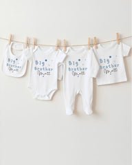 A row of four white baby clothes with the text "Big Brother Matt" printed on them, hanging on a clothesline.